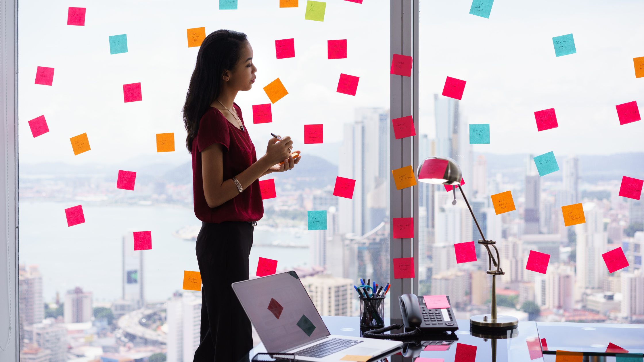 A woman organizing her thoughts with the sticky notes pasted on the wall glass