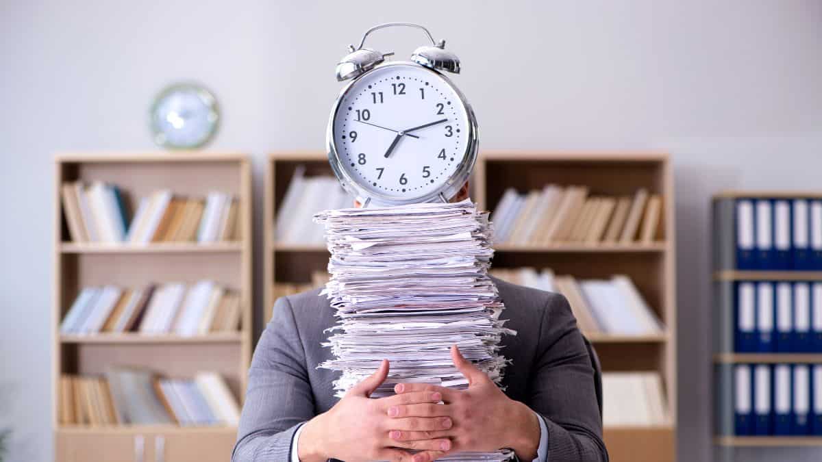 A man holding a bunch of paper with a clock on the top